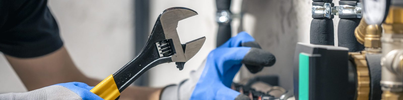 A man installs a heating system in a house and checks the pipes with a wrench. A man installs a heating system in a house and checks the pipes with a wrench. Adjusting heating valves in a residential building. A plumbing and heating technician works.